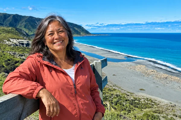 Smiling New Zealand woman over 50 at a lookout on the Wainuiomata Coast near Wellington